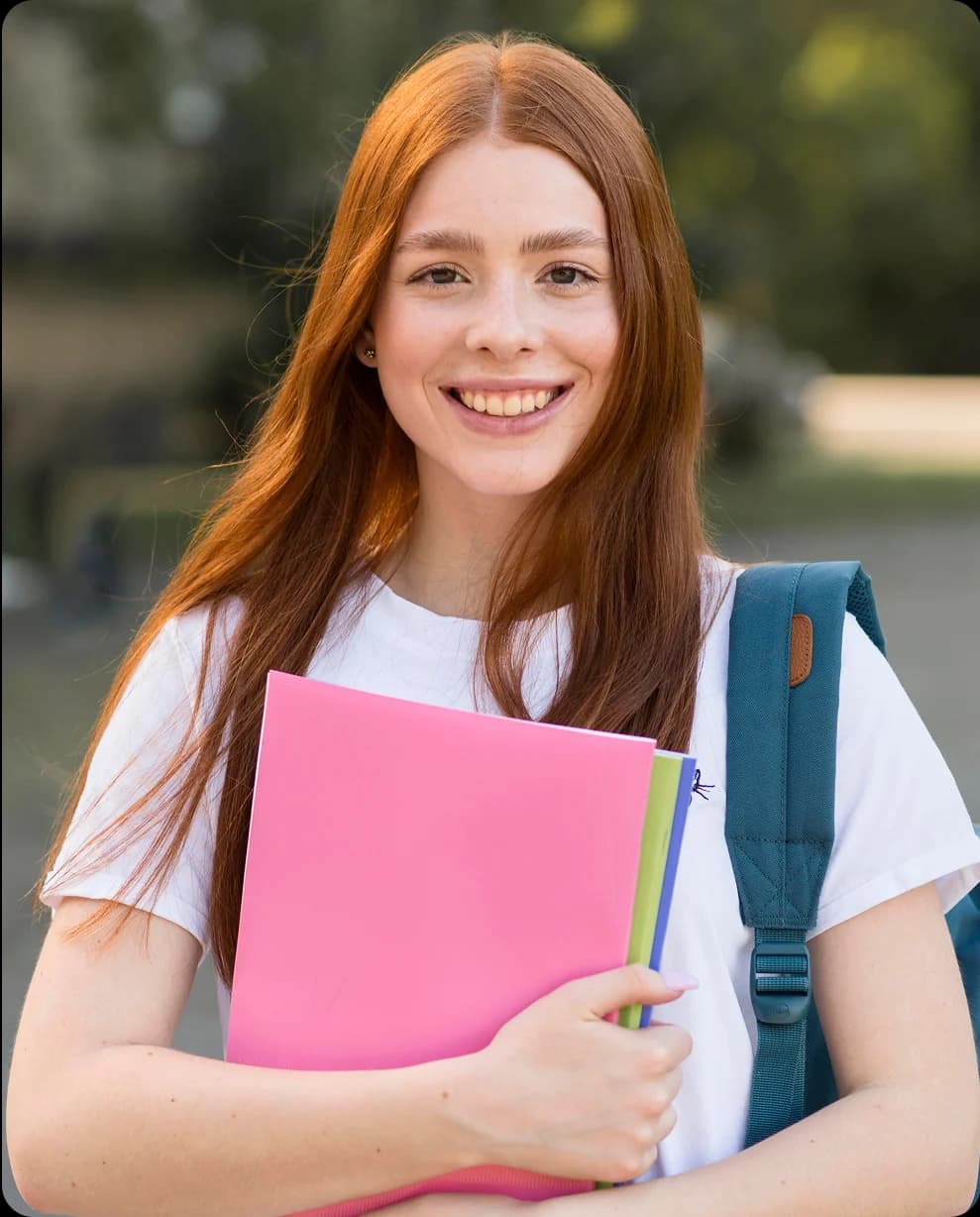 A student holding folders and smiling.